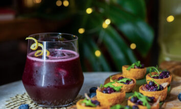 A festive blueberry spirit free cocktail with duck canapés and holiday lights.