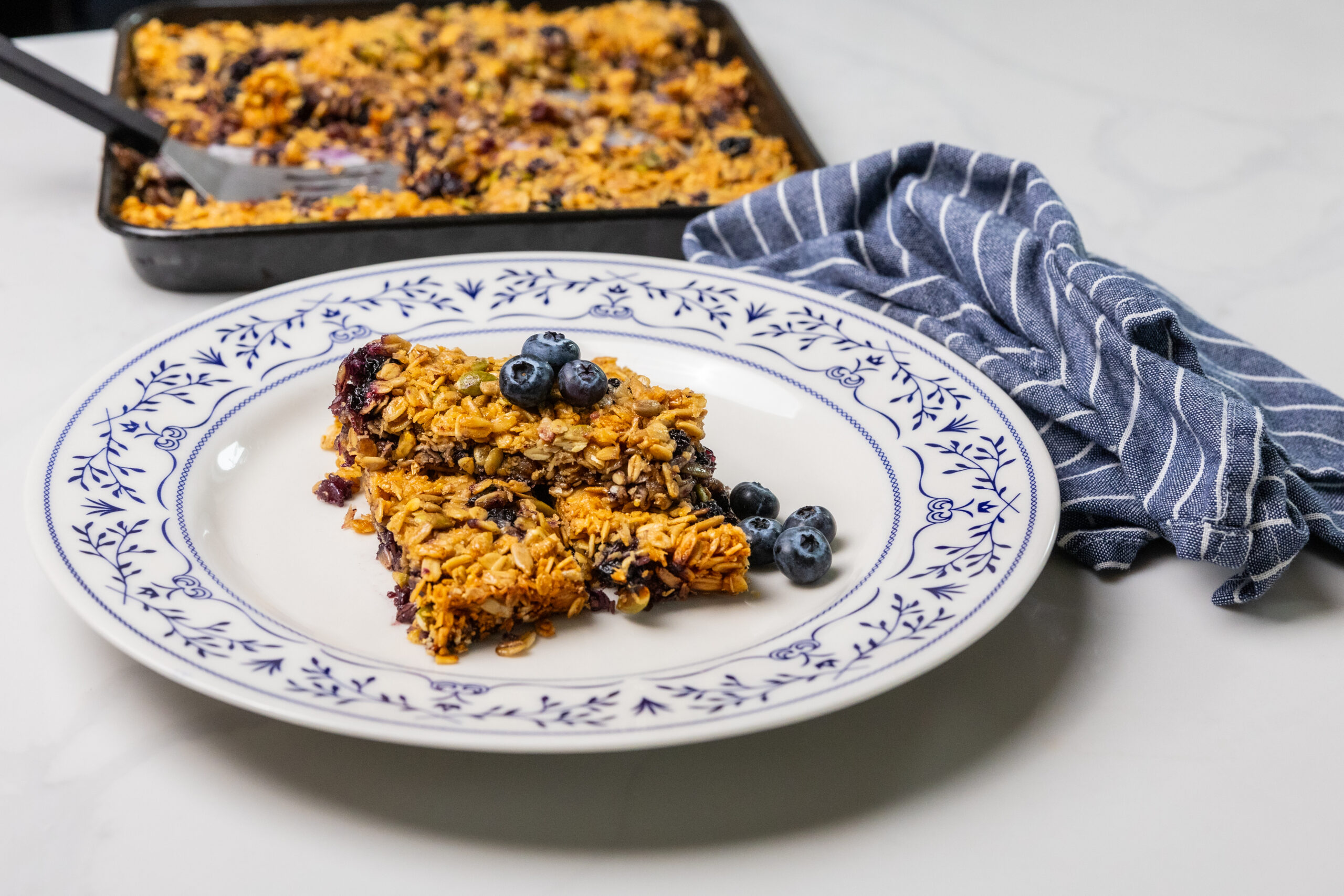 Healthy homemade Blueberry Bars made with Silver Valley Farms blueberries, plated on a white dish with an ornate blue border.